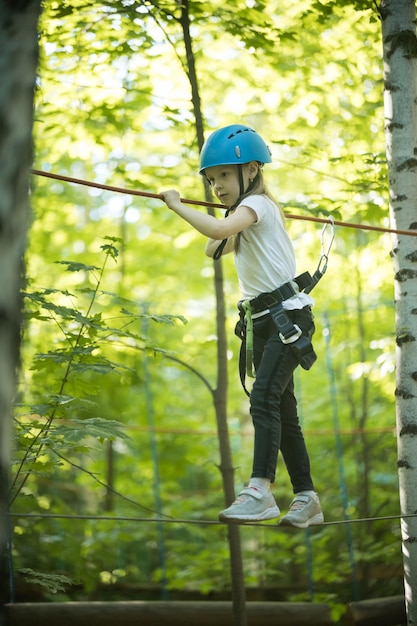 Una bambina in piedi sulla corda con l'assicurazione completa e divertirsi