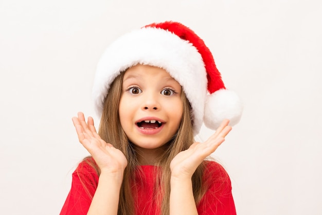 Una bambina in posa su un muro bianco in un cappello di Natale.