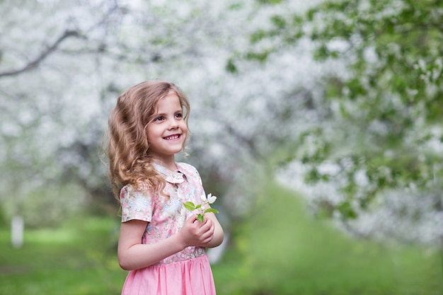 Una bambina in un abito rosa in un giardino fiorito