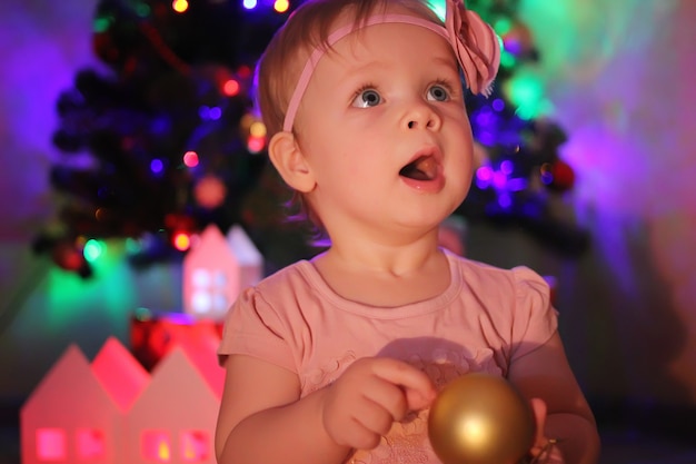 Una bambina in un abito rosa, sullo sfondo di un albero di Natale