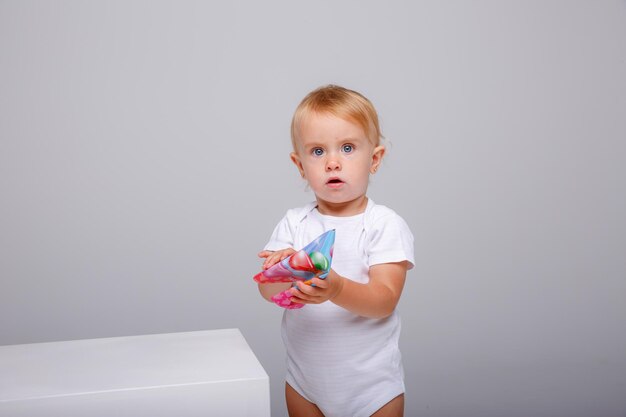 una bambina in un body bianco festeggia il suo compleanno su uno sfondo bianco