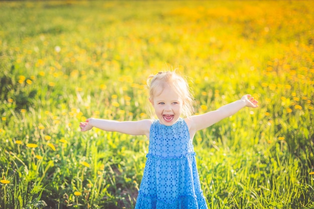 Una bambina in un vestito blu urla felicemente