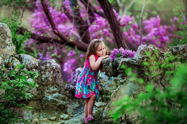 Una bambina in una foresta con alberi in fiore