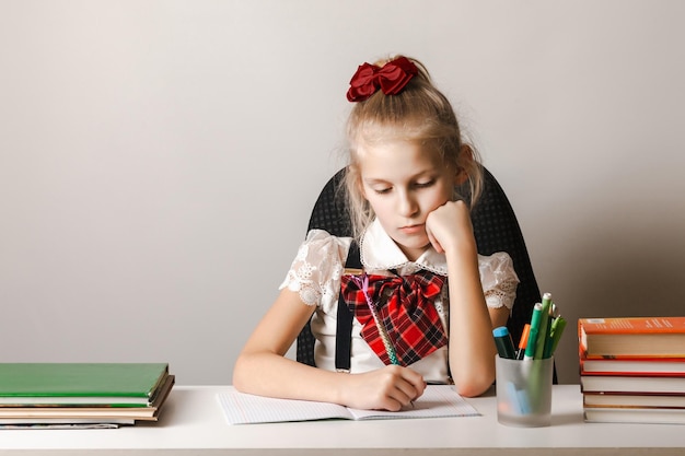 Una bambina in uniforme scolastica sta facendo i compiti su un quaderno