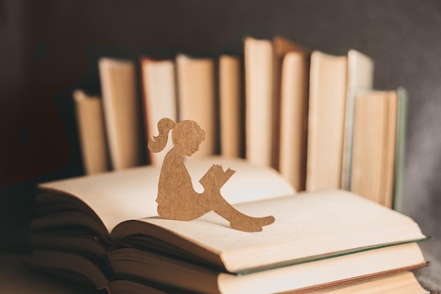 Una bambina legge un libro dei sogni sullo sfondo di vecchi libri