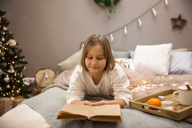 Una bambina legge un libro su un letto in camera da letto