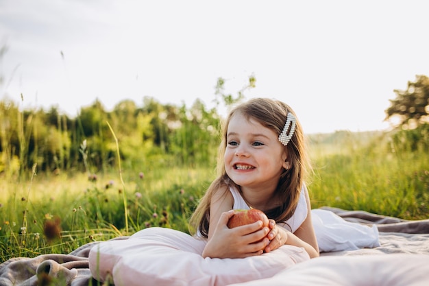 Una bambina mangia una mela da un albero