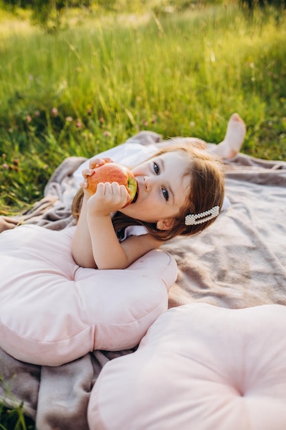 Una bambina mangia una mela da un albero