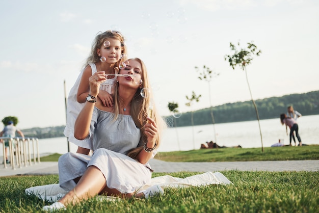 Una bambina meravigliosa fa le bolle con sua madre nel parco.