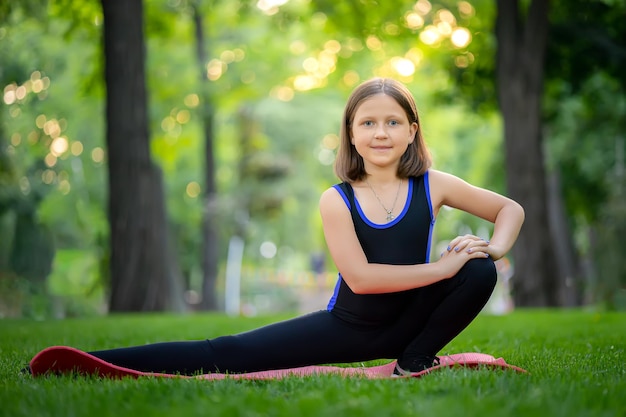 Una bambina nel parco si esibisce allungando la gamba accovacciata