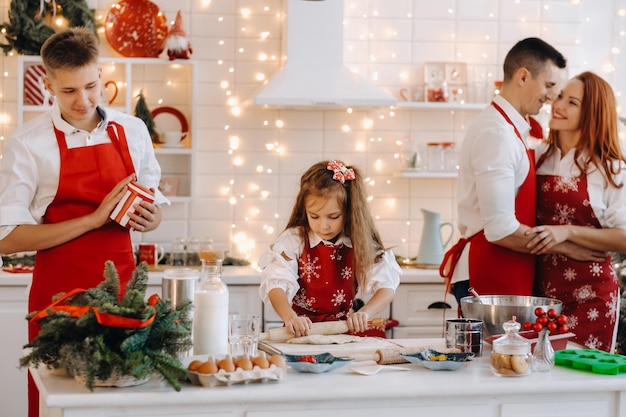 Una bambina nella cucina di Capodanno fa l'impasto e la sua famiglia l'aiuta