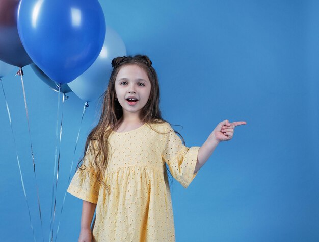 Una bambina punta il dito di lato su uno sfondo blu