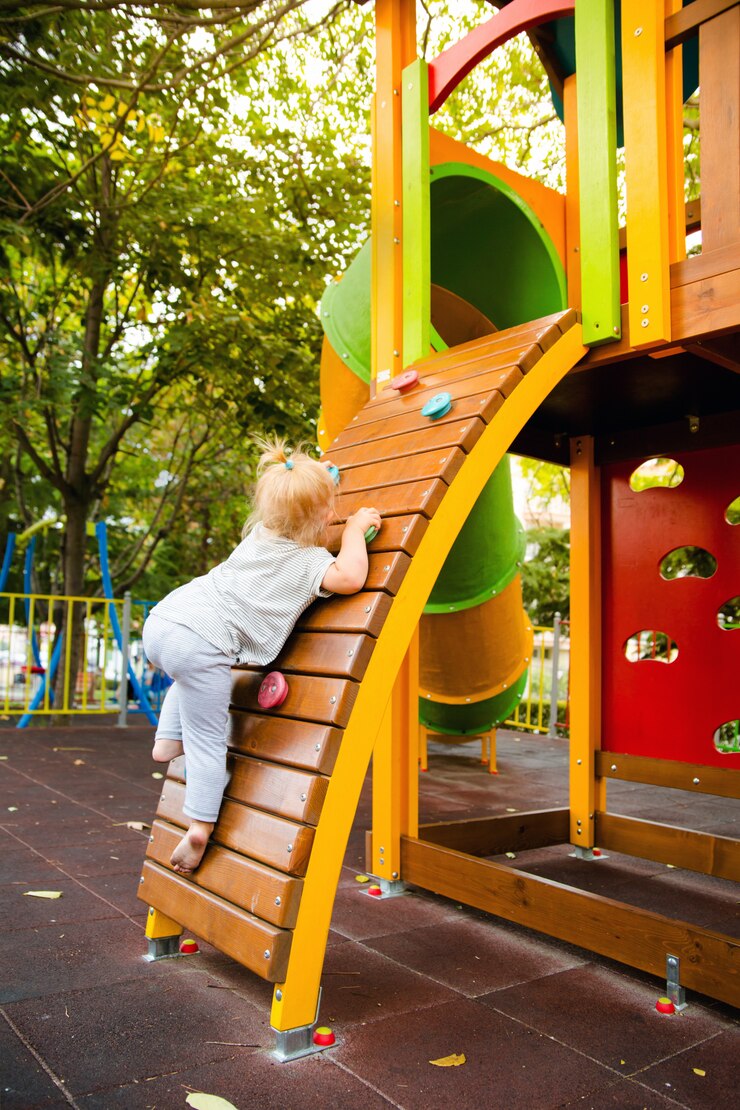 Una bambina sale la parete da arrampicata sullo scivolo per bambini nel parco giochi.