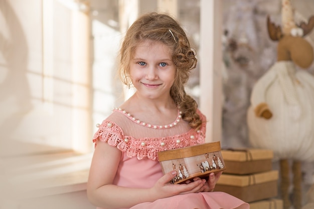 Una bambina si siede sotto il portico di una casa addobbata per Natale e Capodanno