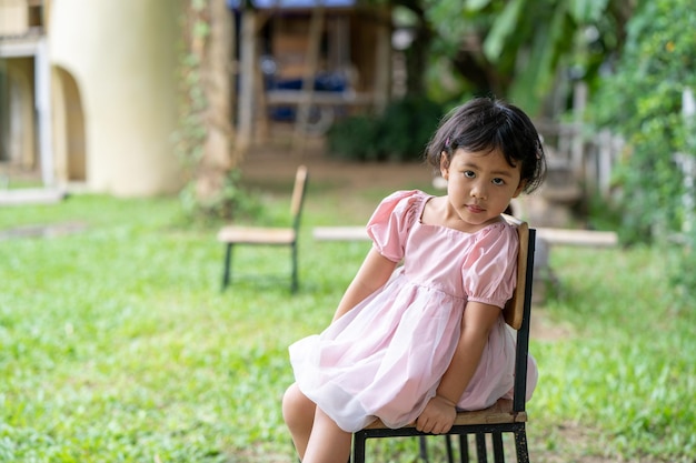 Una bambina si siede su una sedia in un giardino.