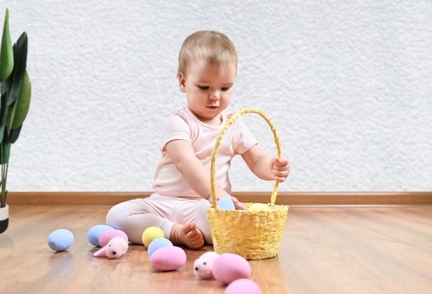 Una bambina si siede sul pavimento e gioca con le uova di Pasqua colorate