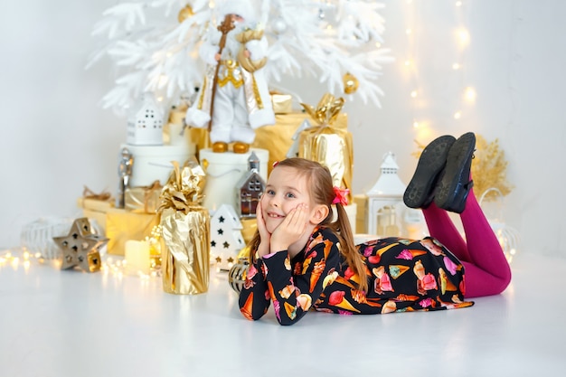 Una bambina si trova vicino all'albero di Capodanno e sorride.