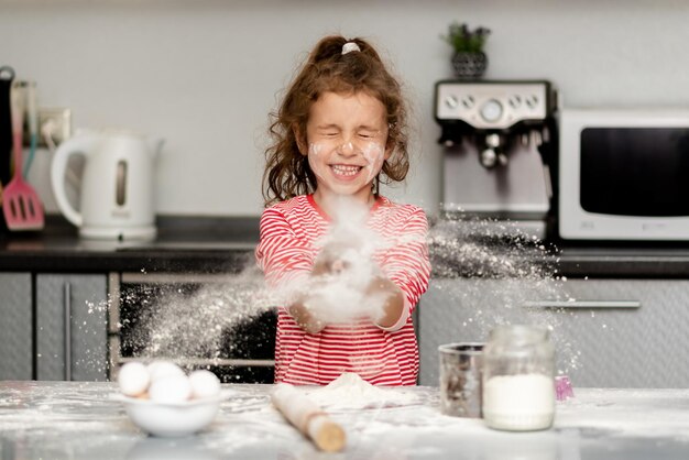 Una bambina sorridente prepara biscotti e gioca con la farina House Comfort Kitchen Cooking Fan