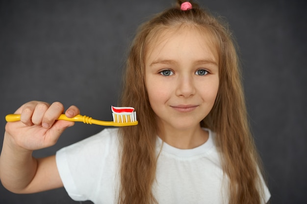 Una bambina sorridente tiene uno spazzolino da denti con dentifricio