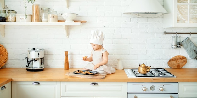 Una bambina sta giocando a cuocere in cucina biscotti dolci Il bambino è solo a casa