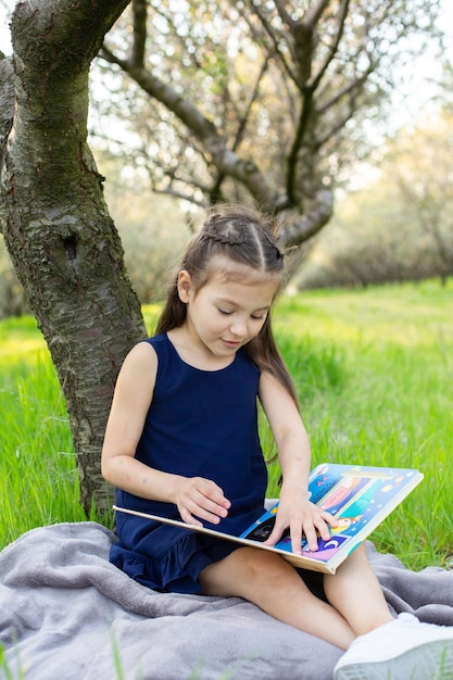 una bambina sta leggendo un libro nel parco