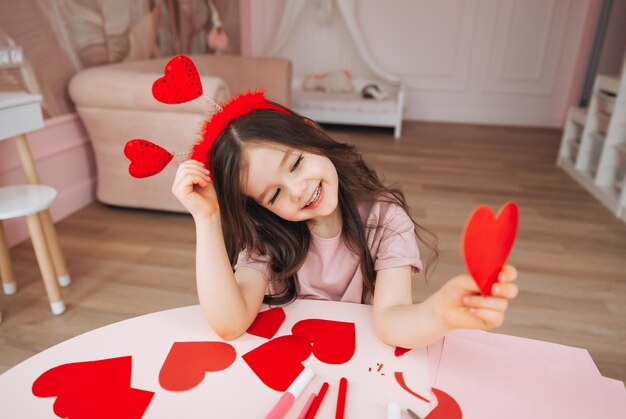 Una bambina tiene le carte rosse a forma di cuore che chiude gli occhi con loroil giorno di san valentino