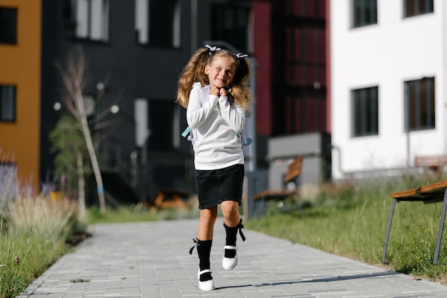 una bambina va a scuola attraverso il parco lungo il sentiero. concetto di formazione a distanza. scolaretta