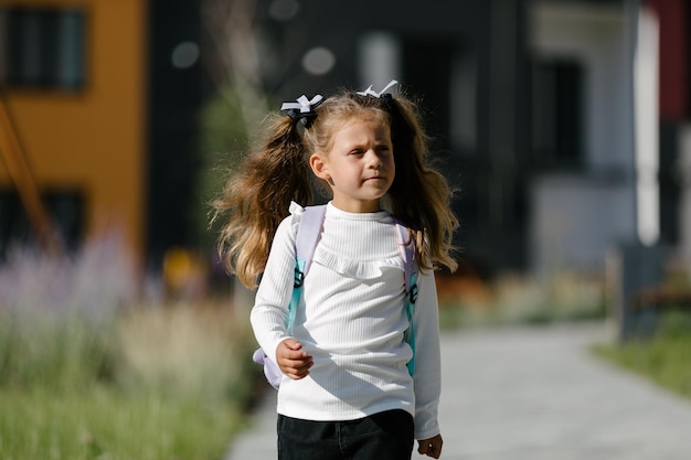 una bambina va a scuola attraverso il parco lungo il sentiero. concetto di formazione a distanza. scolaretta