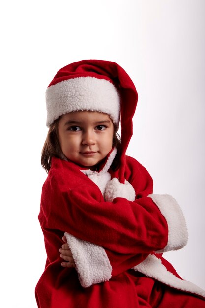 Una bambina vestita da Babbo Natale su sfondo bianco