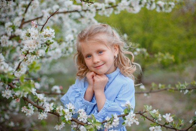 Una bambina vicino a un albero in fiore in primavera