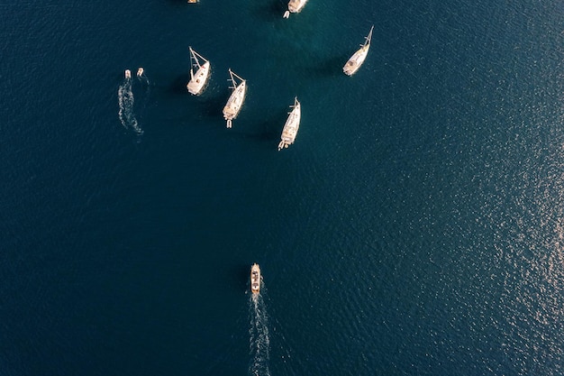 Una barca a motore naviga attraverso il mare verso una regata a vela vista dall'alto