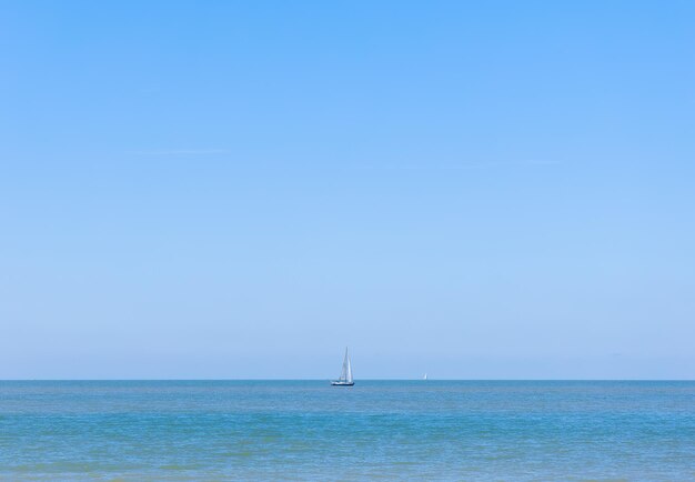 Una barca a vela scivola sulle acque cristalline dell'oceano contro un cielo soleggiato