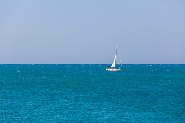 Una barca a vela sta navigando nell'oceano con una barca a vela bianca in lontananza.