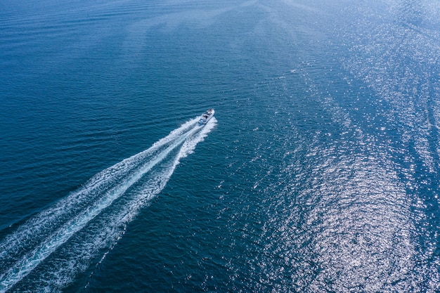 Una barca ad alta velocità o uno yacht manovra sulla superficie del mare o dell'oceano. Vista aerea.