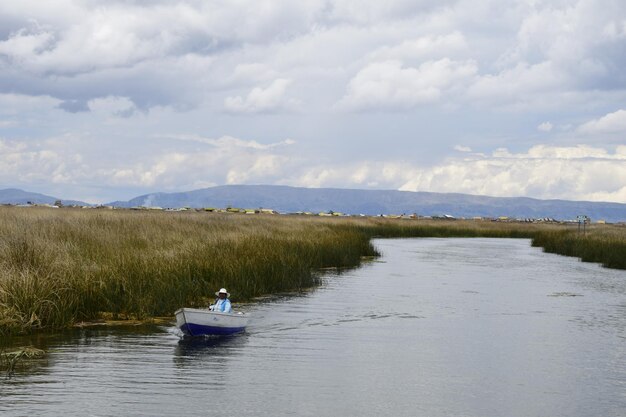 Una barca con gente del posto percorre un piccolo corso d'acqua sul lago Titicaca fino alle isole di paglia di Puno, in Perù