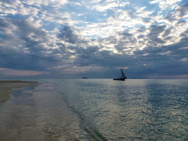 Una barca da pesca sta navigando sul mare vicino alla spiaggia sullo sfondo del cielo serale