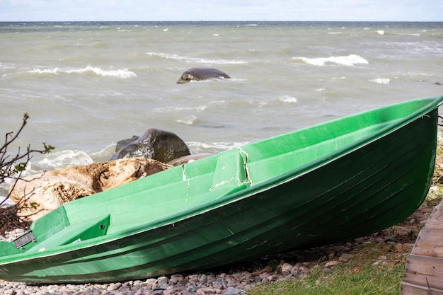 Una barca di plastica verde rotta sulla riva della spiaggia