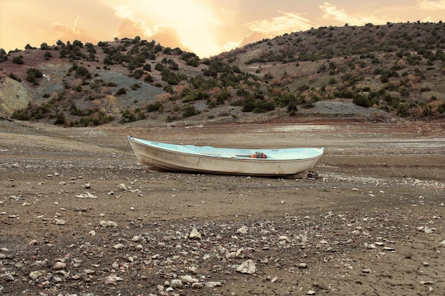 Una barca è seduta a terra davanti a una montagna.