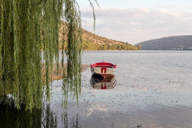 Una barca sullo sfondo della città lago Orestiada nella città di Kastoria in serata Macedonia nord-ovest della Grecia