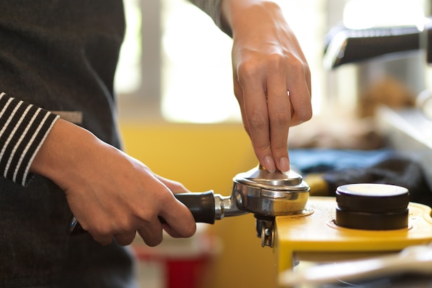 Una barista che preme caffè macinato per la preparazione