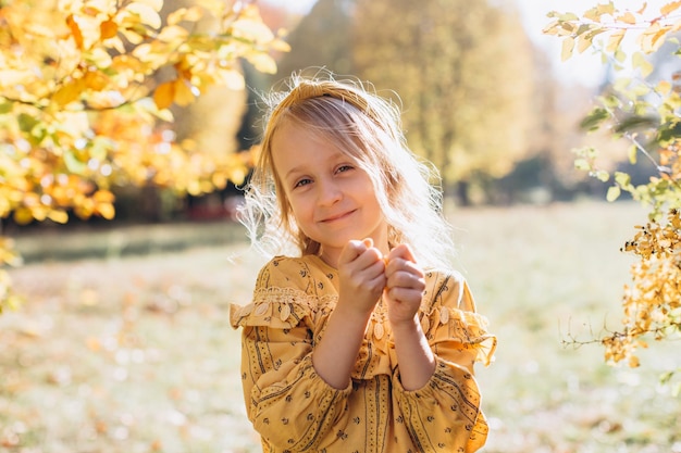 Una bella bambina bionda sta camminando in un parco autunnale