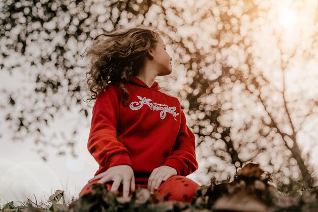 Una bella bambina che gioca con le foglie in autunno