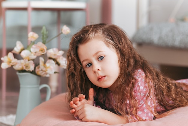 Una bella bambina giace sul pavimento nella stanza dei bambini e sogna. Le emozioni dei bambini