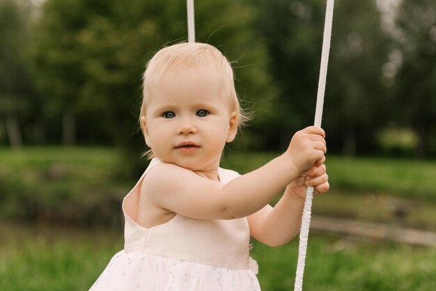 Una bella bambina in un cestino con un palloncino e una torta festeggia il suo primo compleanno