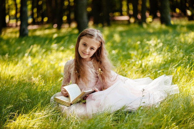 Una bella bambina legge un libro nel parco.