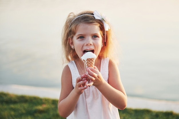 Una bella bambina mangia un gelato vicino all'acqua