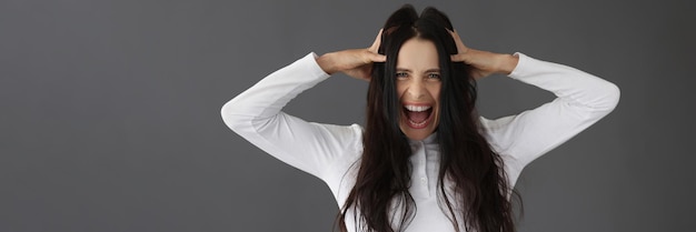 Una bella bruna urla tenendo la testa primo piano concetto stress emozioni negative critiche