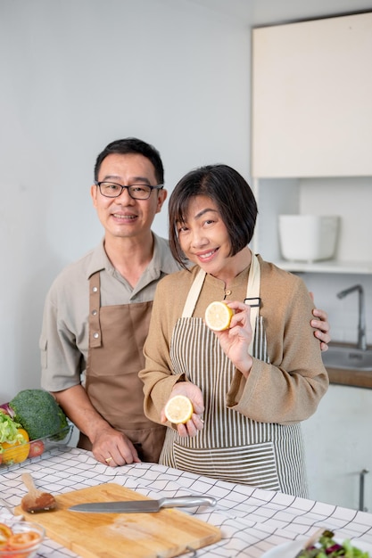 Una bella coppia asiatica è in cucina indossando un grembiule che si prepara a cucinare la cena insieme