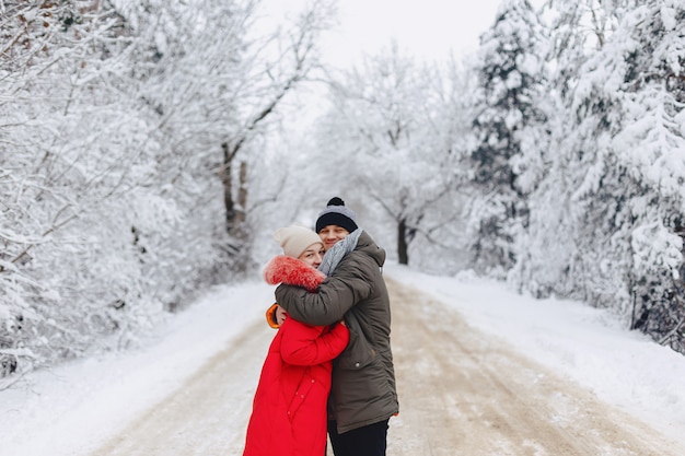 Una bella coppia di famiglia camminando su una strada innevata nel bosco