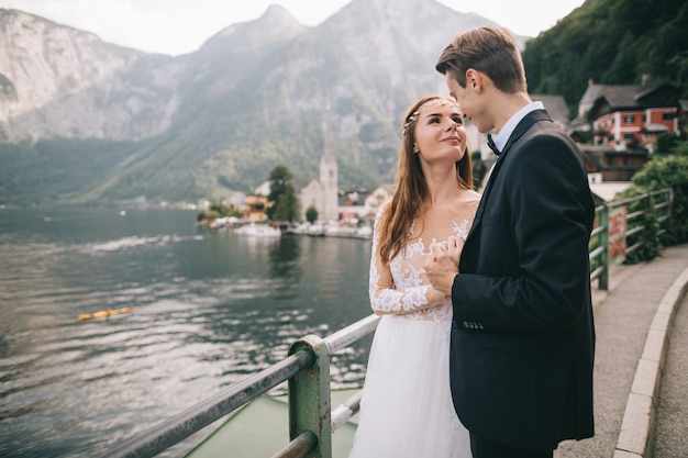 Una bella coppia di sposi cammina vicino a un lago in una fata cittadina austriaca, Hallstatt.